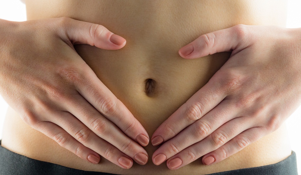 Slim woman touching her belly on white background